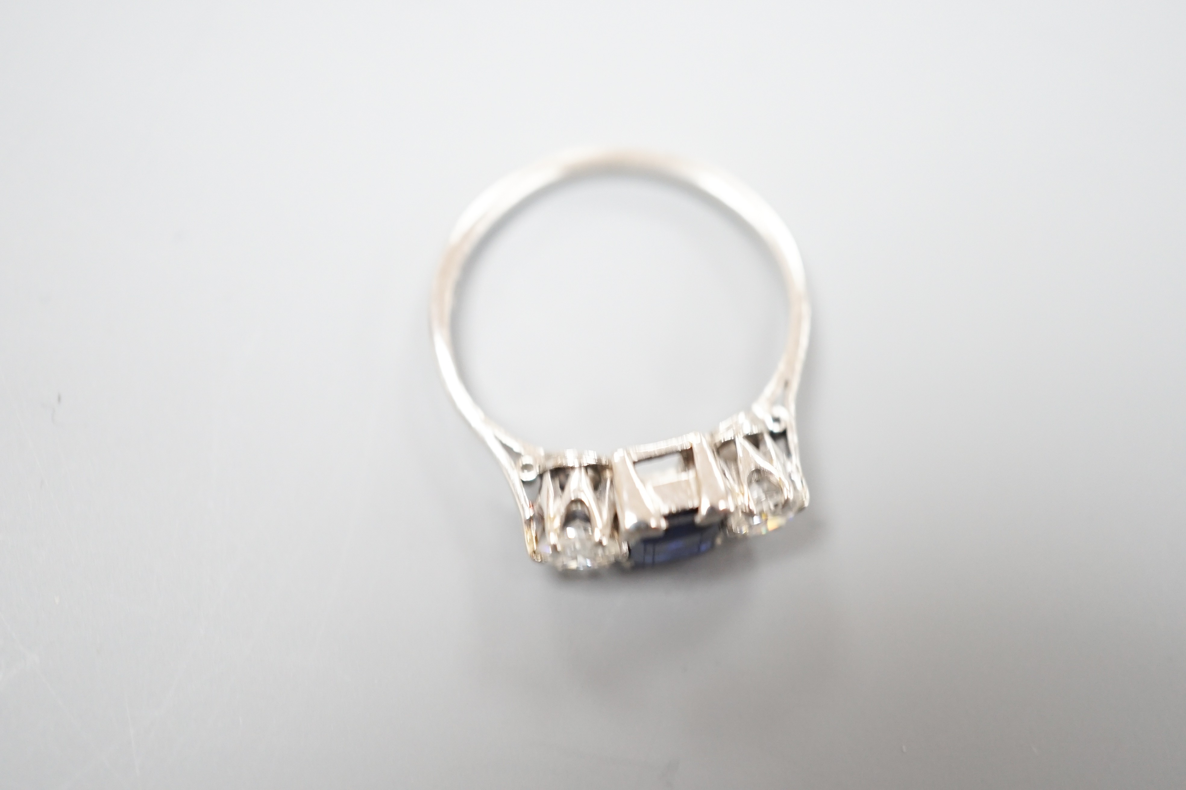 A white metal (stamped plat), sapphire and diamond set three stone ring, size K, gross weight 3.6 grams.